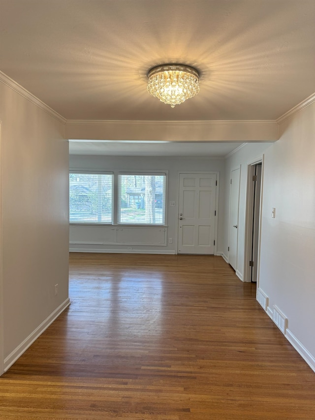 foyer with a chandelier, crown molding, wood finished floors, and baseboards