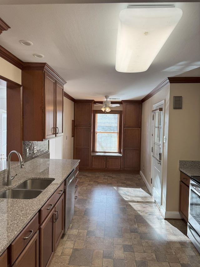 kitchen featuring a sink, appliances with stainless steel finishes, baseboards, stone tile floors, and crown molding