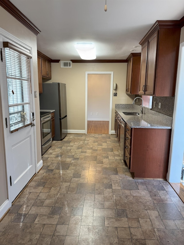 kitchen with a sink, stainless steel appliances, baseboards, stone tile floors, and ornamental molding