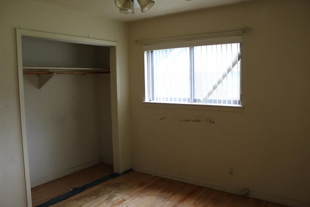 unfurnished bedroom with baseboards, wood finished floors, and a closet