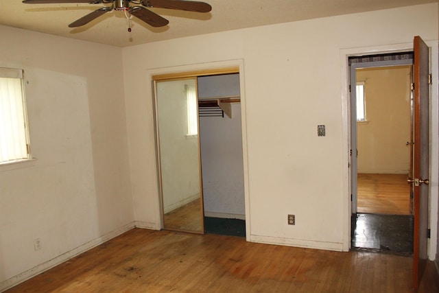 unfurnished bedroom with a closet, baseboards, ceiling fan, and wood finished floors