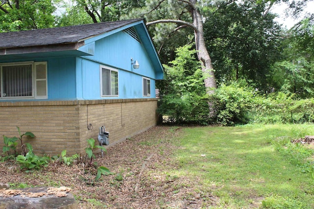 view of home's exterior with a lawn, brick siding, and a shingled roof