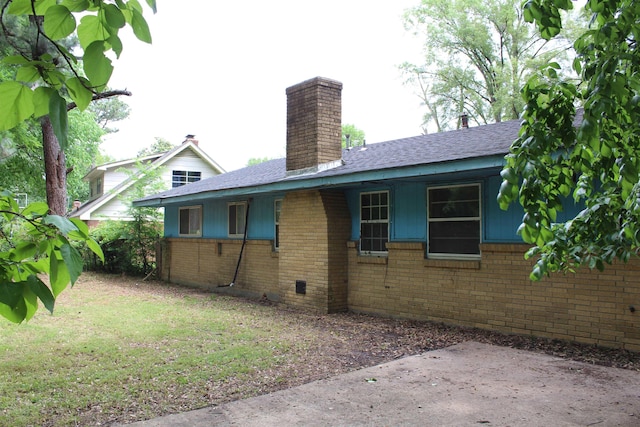 view of side of home with roof with shingles, a chimney, and brick siding