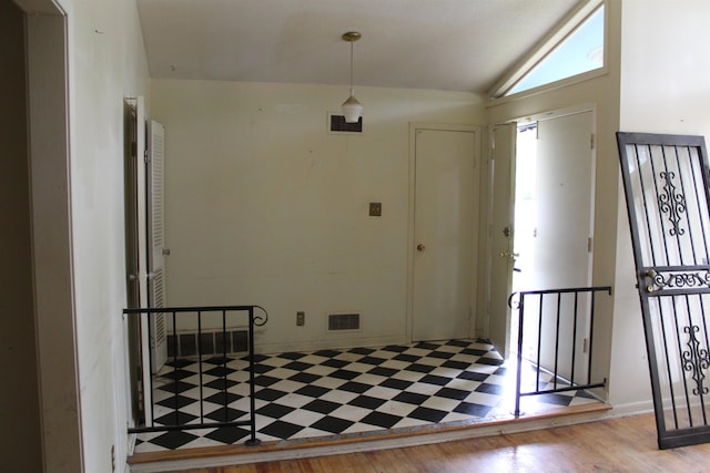 foyer featuring visible vents, wood finished floors, and lofted ceiling