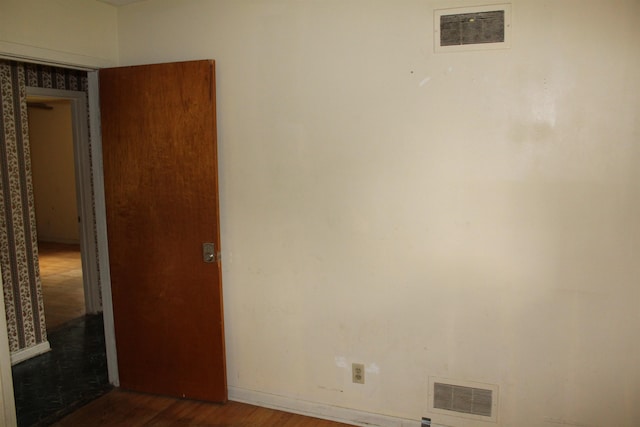 unfurnished room featuring baseboards, visible vents, and wood finished floors