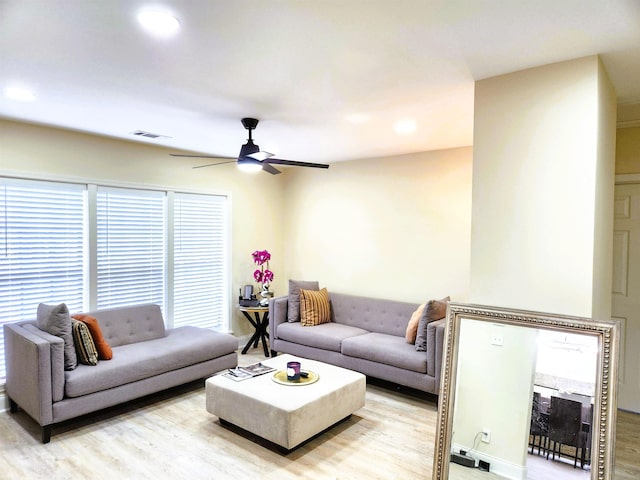 living room with ceiling fan, light wood finished floors, visible vents, and a wealth of natural light