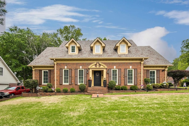 cape cod-style house with a front lawn, brick siding, and roof with shingles