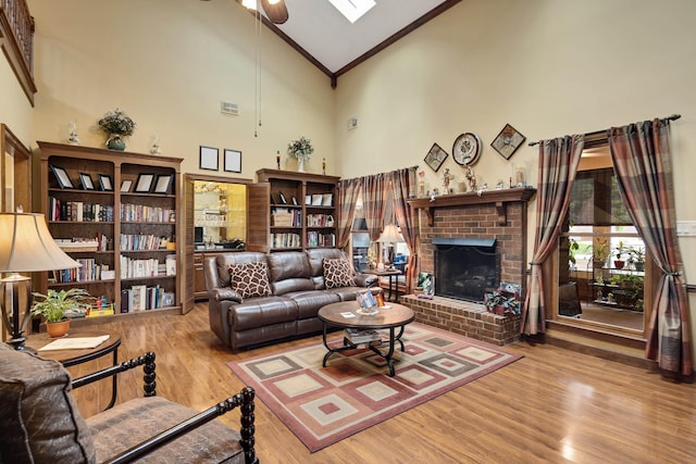 living area featuring a ceiling fan, ornamental molding, high vaulted ceiling, wood finished floors, and a fireplace