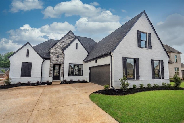 view of front of home featuring a front lawn, brick siding, driveway, and roof with shingles
