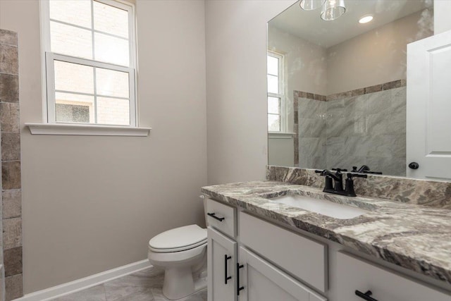 bathroom with vanity, toilet, baseboards, and plenty of natural light