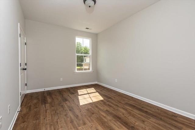 unfurnished room with visible vents, baseboards, and dark wood-style floors