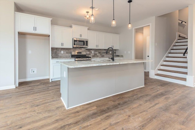 kitchen with wood finished floors, a sink, visible vents, appliances with stainless steel finishes, and tasteful backsplash
