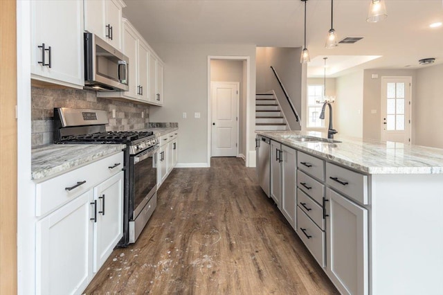 kitchen with a sink, backsplash, dark wood-style floors, white cabinets, and appliances with stainless steel finishes