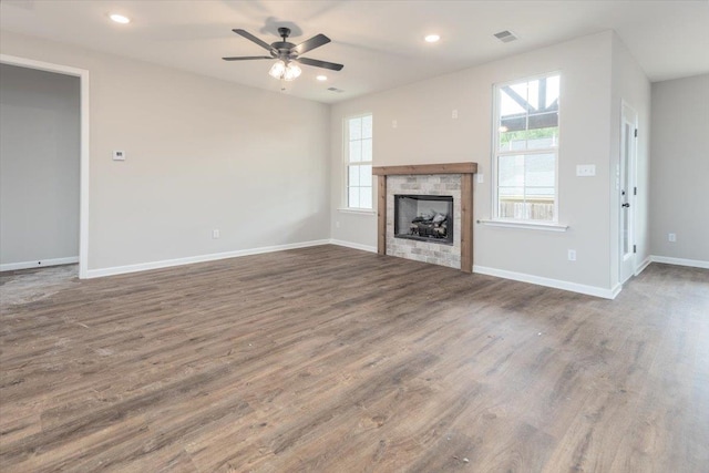 unfurnished living room with a wealth of natural light, a ceiling fan, and wood finished floors