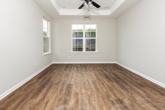 empty room featuring baseboards, a tray ceiling, ceiling fan, and wood finished floors