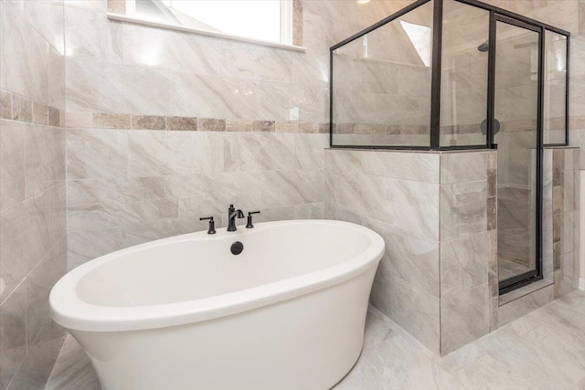 full bath featuring a shower stall, tile walls, and a freestanding tub