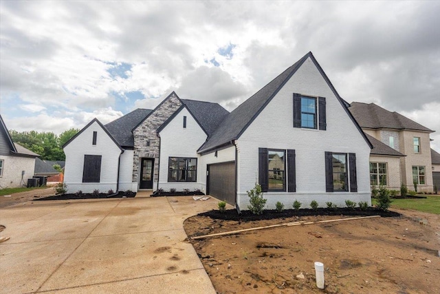 french provincial home featuring a garage and brick siding