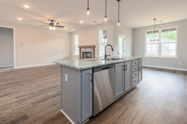 kitchen with a sink, open floor plan, gray cabinets, stainless steel dishwasher, and dark wood-style flooring