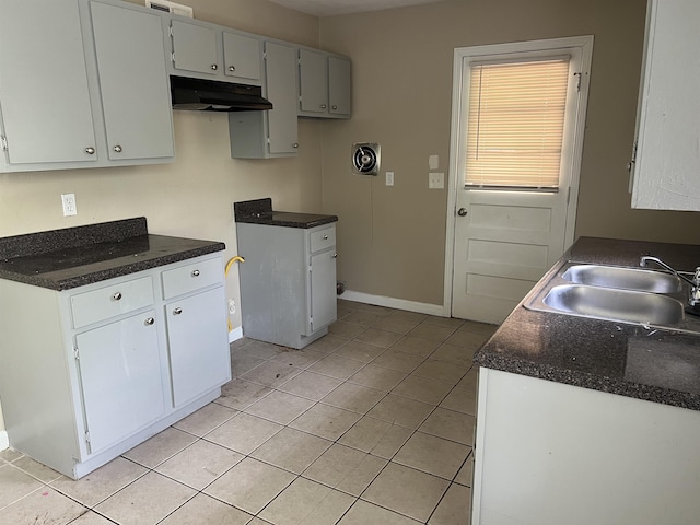 2997 Atmore St, Memphis, TN 38118 - kitchen featuring a sink, under cabinet range hood, light tile patterned floors, baseboards, and dark countertops
