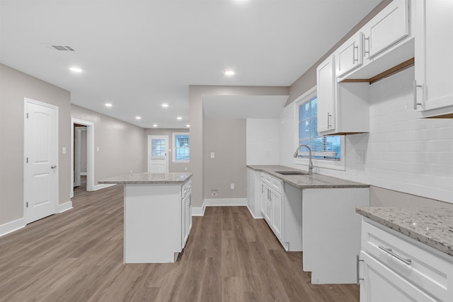 kitchen featuring tasteful backsplash, light stone countertops, and a sink
