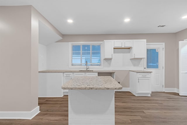 kitchen featuring baseboards, a sink, decorative backsplash, wood finished floors, and white cabinets