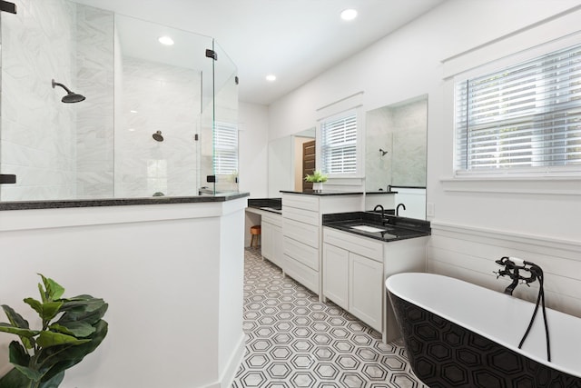 full bath featuring walk in shower, vanity, a freestanding tub, and a healthy amount of sunlight