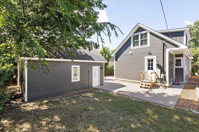 rear view of house with an outdoor structure, a lawn, and a patio