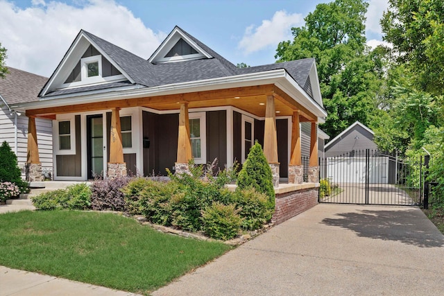 craftsman-style home with driveway, stone siding, a porch, roof with shingles, and a gate
