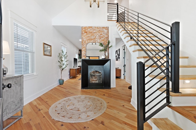 staircase with baseboards, hardwood / wood-style floors, a fireplace, and a high ceiling