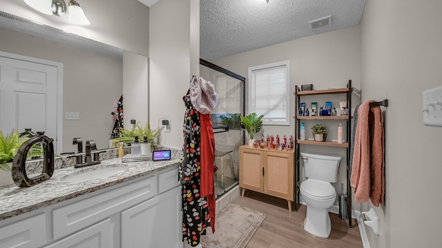 full bath featuring a stall shower, vanity, visible vents, and wood finished floors