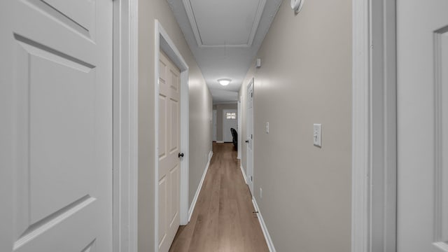 hallway featuring attic access, wood finished floors, and baseboards