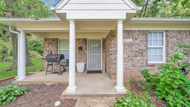 entrance to property with covered porch and brick siding