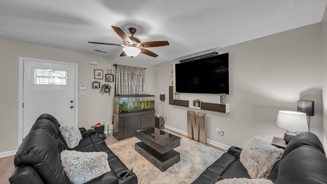 living room with ceiling fan, baseboards, and visible vents