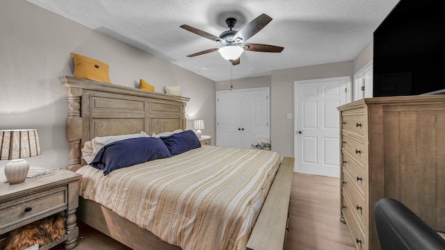 bedroom featuring light wood finished floors, a textured ceiling, a closet, and ceiling fan