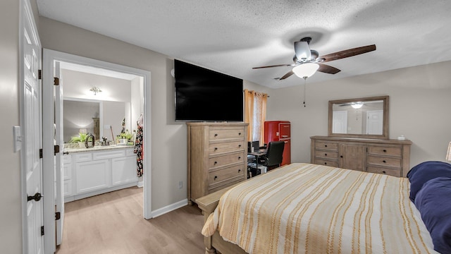 bedroom featuring connected bathroom, light wood-type flooring, a textured ceiling, baseboards, and ceiling fan