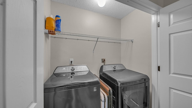laundry area featuring laundry area, a textured ceiling, and washing machine and clothes dryer