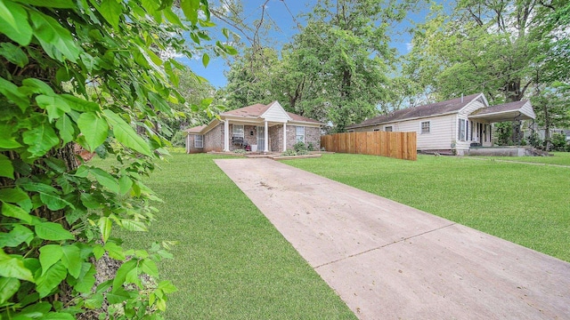 view of front of property with concrete driveway, brick siding, a front lawn, and fence