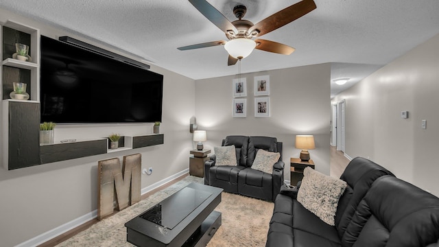 living room featuring baseboards, ceiling fan, and a textured ceiling