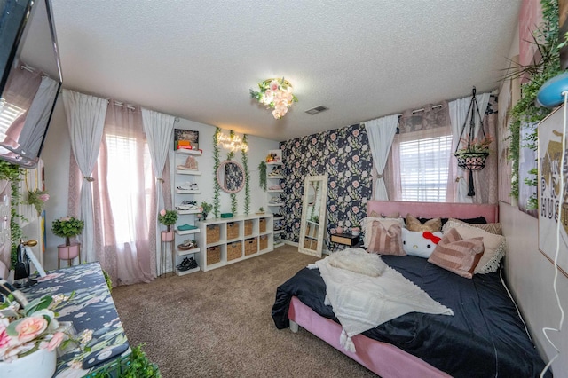 bedroom with multiple windows, a textured ceiling, visible vents, and carpet