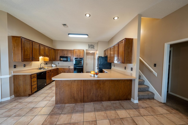 kitchen with visible vents, a sink, a peninsula, black appliances, and light countertops