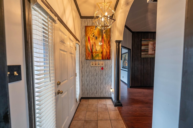 corridor featuring a chandelier, ornamental molding, wallpapered walls, and tile patterned floors