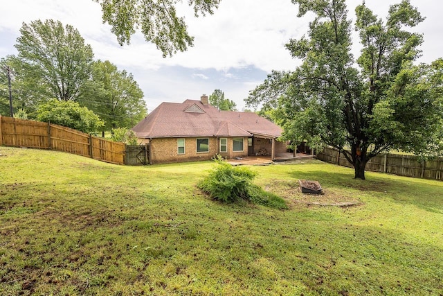rear view of property featuring a yard, a chimney, a patio area, and a fenced backyard