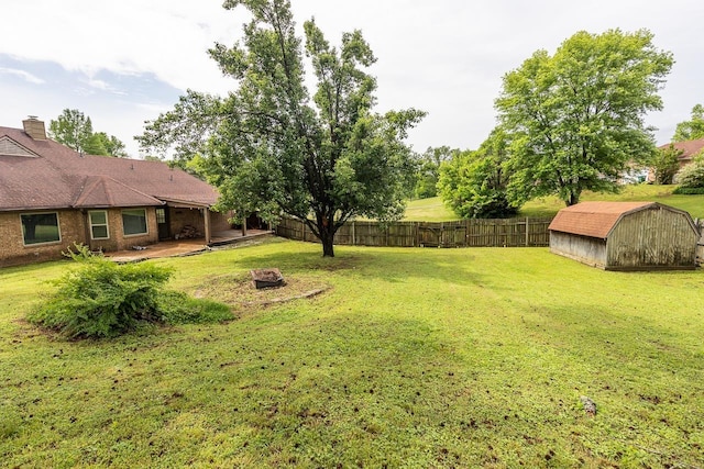 view of yard featuring an outdoor structure, a fire pit, a storage unit, a patio, and a fenced backyard