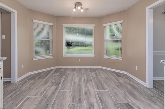 spare room featuring light wood-style flooring and baseboards