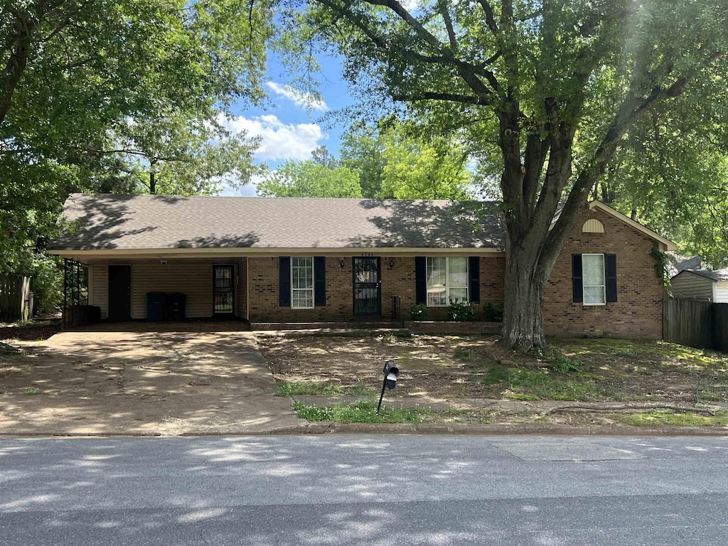 ranch-style house with driveway, brick siding, and a carport