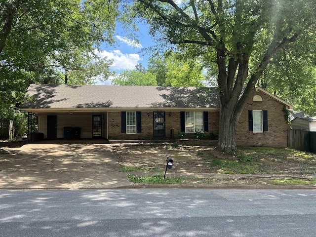 ranch-style house with driveway, brick siding, and a carport