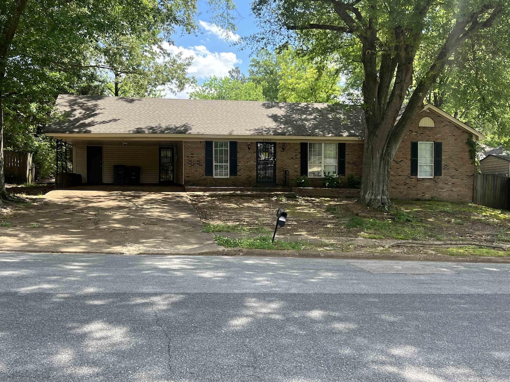 ranch-style home with brick siding, driveway, and a carport