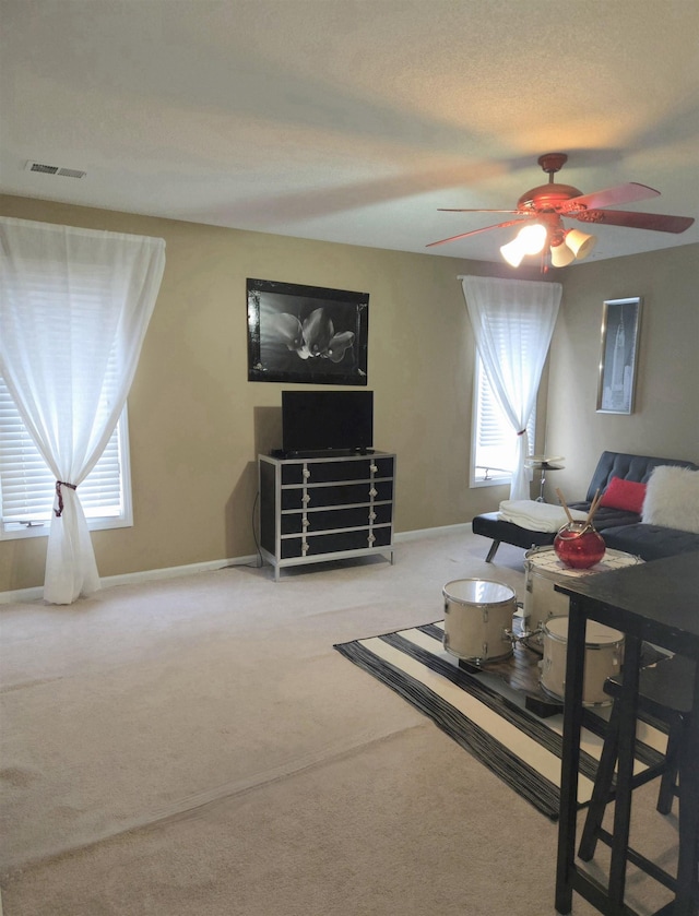 carpeted living area with baseboards, a ceiling fan, and visible vents