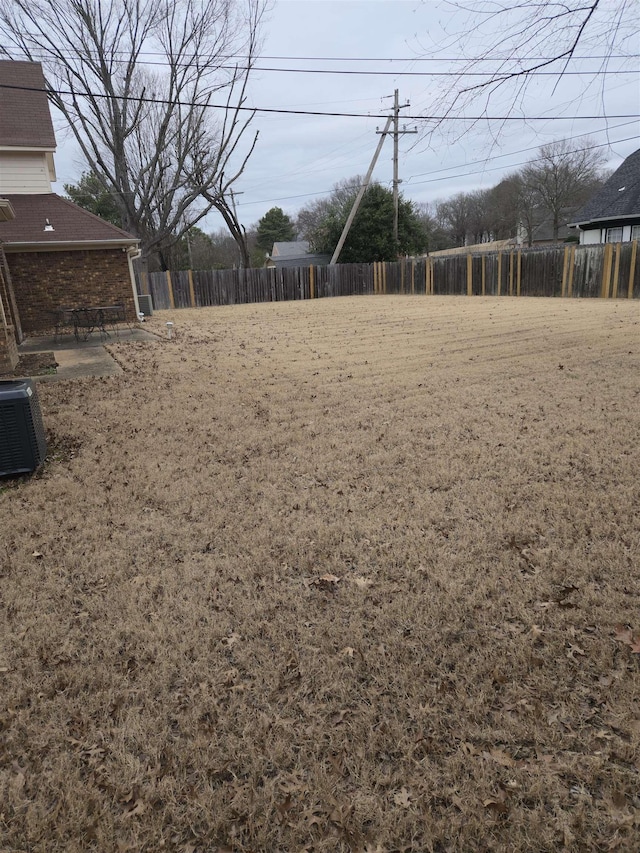 view of yard featuring fence and central AC
