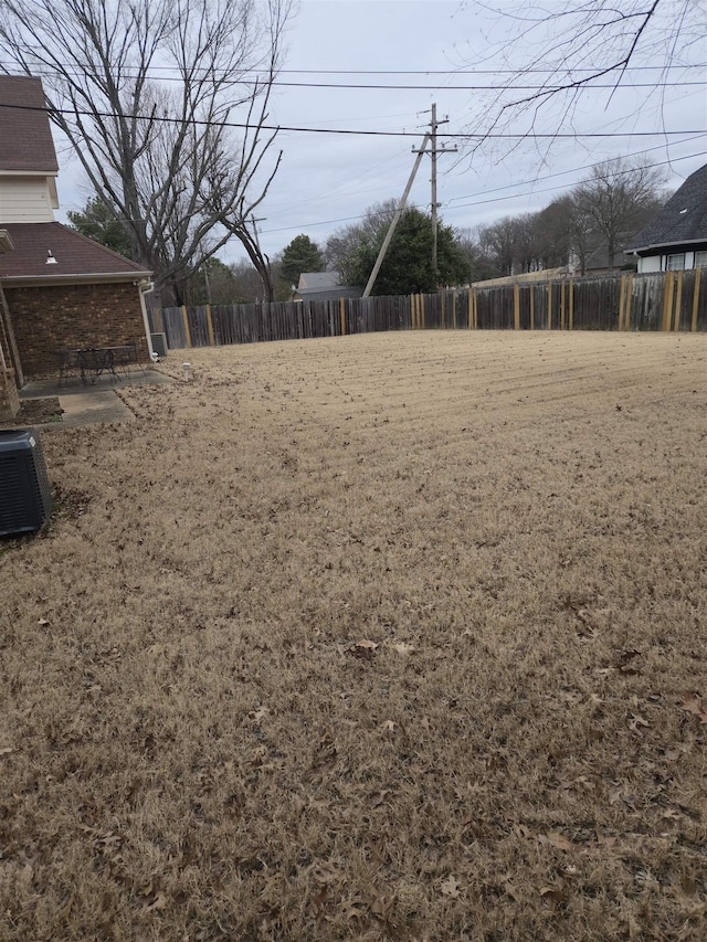 view of yard featuring fence and central AC